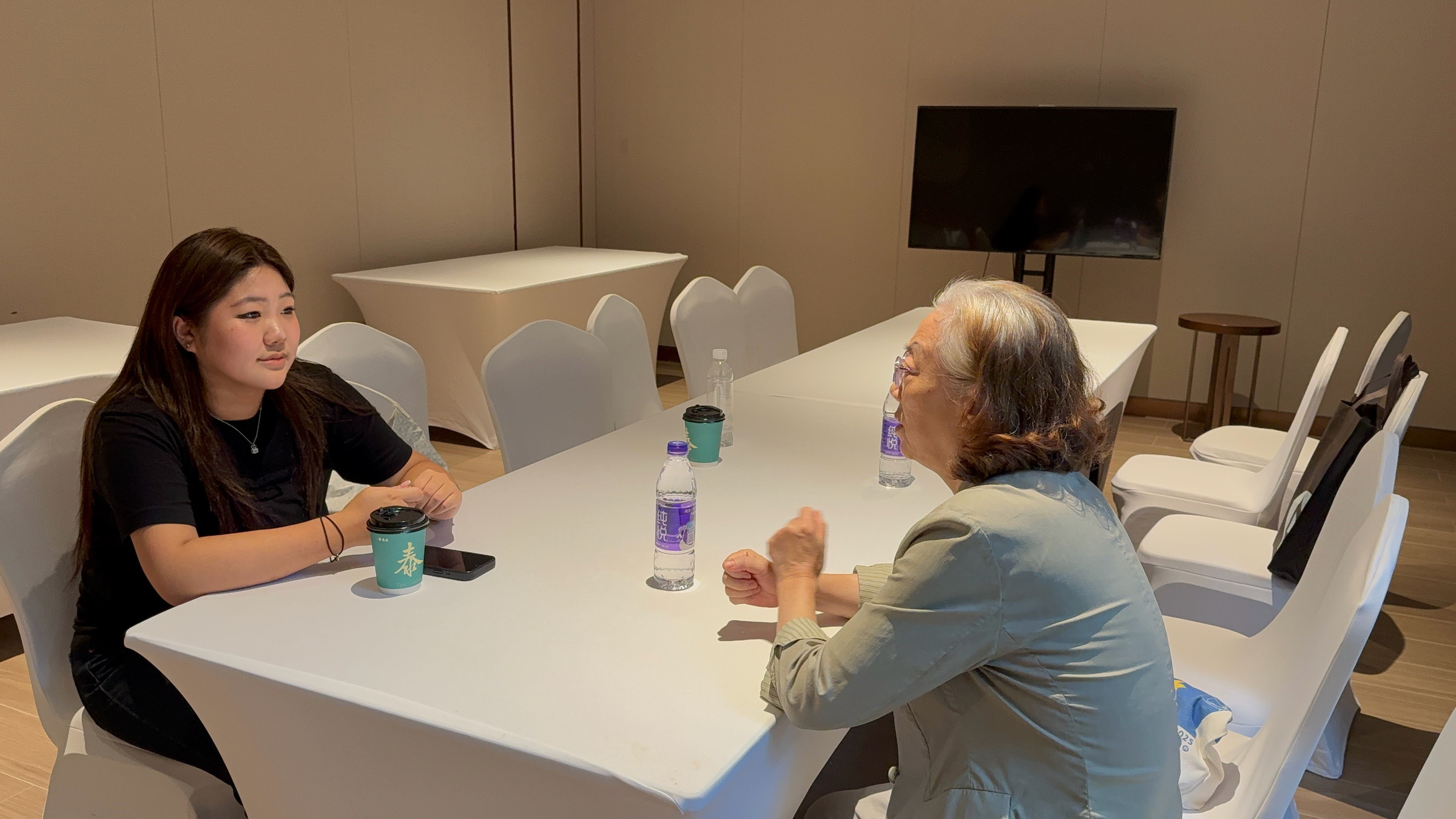 Jessica speaking with an older adult across a white table