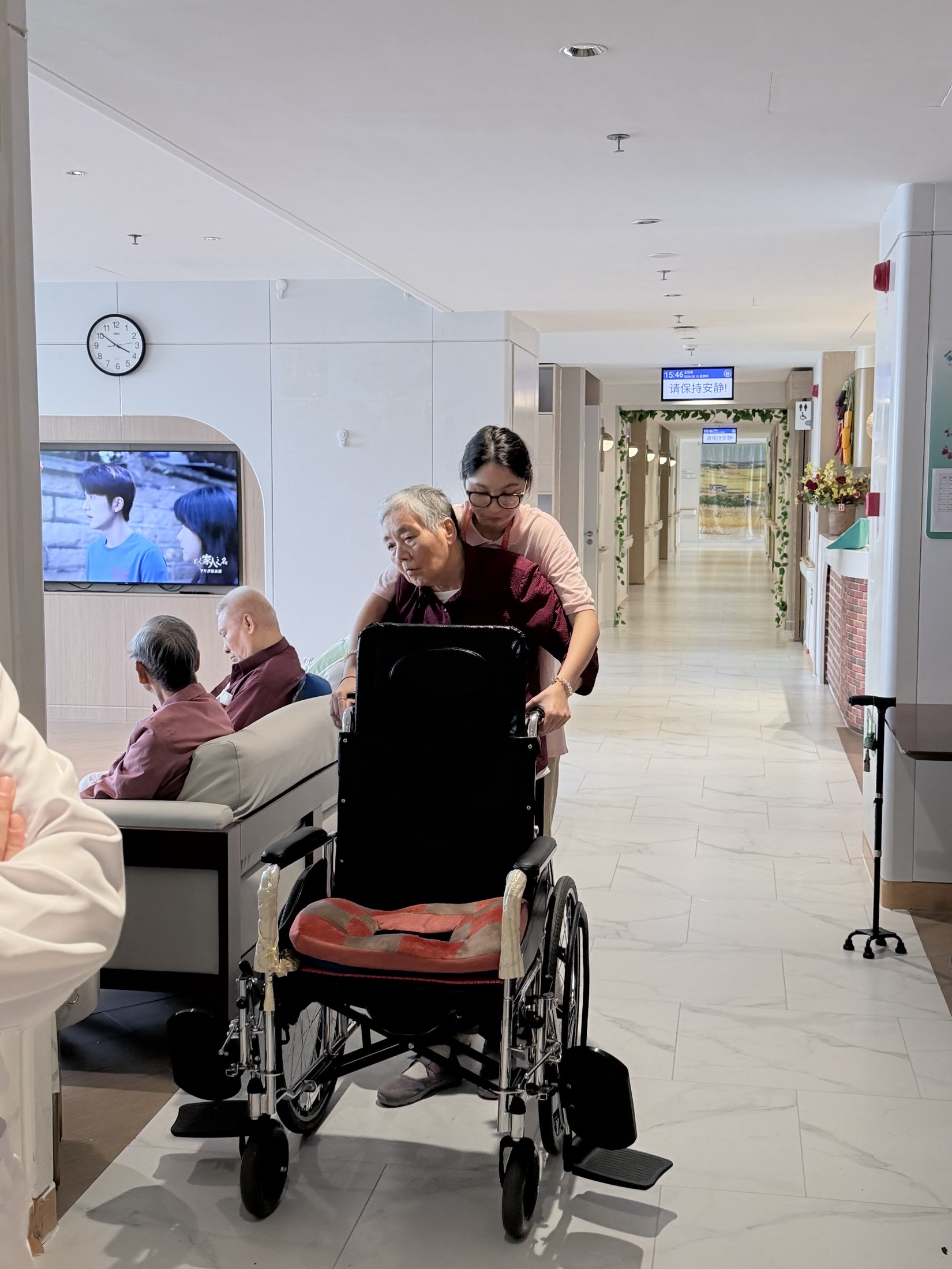 A caregiver assisting an older resident in a wheelchair